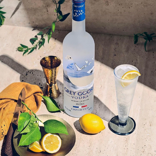 Grey Goose vodka bottle with a cocktail glass and lemon on a textured surface