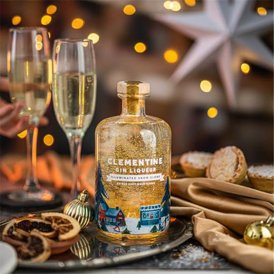 Bottle of Clementine Gin Liqueur on a festive table with glasses and decorations.