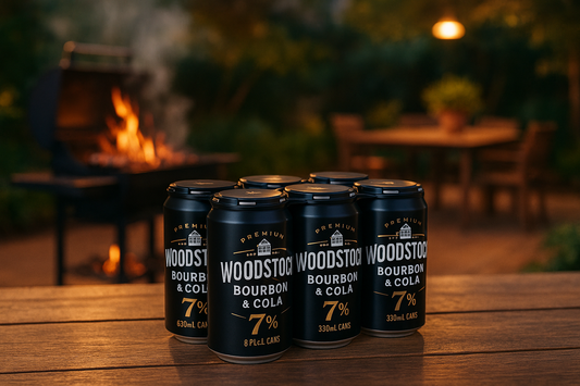 Woodstock 7% Bourbon & Cola 6 Pack 330mL Cans
 with a background of a flash bbq area